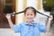 Smiling little Asian baby girl in school uniform holding her two tied ponytails hairs