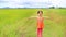 Smiling little Asian child girl stretch arms and relaxed at the young green paddy fields with mountain and cloud sky