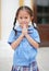 Smiling little Asian girl in school uniform is pay respect Wai