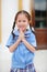 Smiling little Asian girl in school uniform is pay respect Wai Thai Greetings