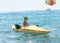 Smiling little baby boy in green baseball cap kayaking at tropical ocean sea in the day time. Positive human emotions, feelings, j