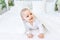 Smiling little baby boy in a white bodysuit lying on the bed, portrait of a child of 6 months. The child is awake