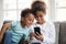 Smiling little black kids play with smartphone together