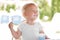 Smiling little blonde toddler boy eating delicious yogurt sitting outdoor