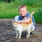 Smiling little boy affectionately embraces a red cat. outdoor