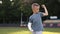 smiling little boy with broken hand is sitting outdoors on sports ground on summer day. 9 years child with a fractured