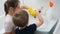 Smiling little boy helping his mother washing and cleaning bathroom at home. Child and adult doing housework