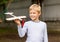 Smiling little boy holding a wooden airplane model