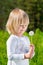 Smiling little boy looking at a dandelion