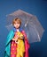 Smiling little boy playing with leaves and looking at camera. Cheerful boy in raincoat with colorful umbrella. Sale for