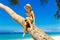 Smiling little boy in a straw hat having fun on a coconut tree on a sandy tropical beach. The concept of travel and family