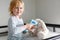 Smiling little child measures temperature of toy fluffy bunny with thermometer