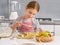 Smiling little girl adding sugar to srudel apple filling