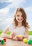 Smiling little girl coloring eggs for easter