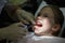 Smiling little girl in the dental office, getting her teeth checked by dentist