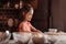 Smiling little girl with flour on face kneading dough