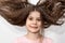 Smiling little girl with flying wavy hair without a front tooth on a white background