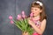 Smiling little girl with hand in a bunch of pink tulips