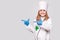 Smiling little girl in medical uniform and blue gloves point to left on free space looking at camera isolated on grey background