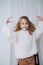 Smiling little girl with messy hair just put on white fluffy knitted sweater