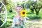 Smiling little girl with pigtail on her head holds sunflower. Childhood concept. Teenager girl with sunflower in garden. Child and