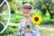 Smiling little girl with a pigtail on her head holds sunflower in garden. Childhood. Child with sunflower. Child enjoying nature o