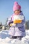 Smiling little girl with shovel shows snow in snowdrift