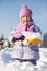 Smiling little girl with shovel shows snow in snowdrift