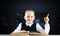 Smiling little girl sitting at desk with open book