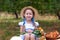 Smiling little girl with two pigtails on her head on picnic in garden. Summer vacation. Copy space. Nature, healthy food concept.