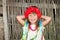 Smiling little girl in a wreath of red flowers and satin ribbons near the wicker fence