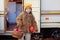 Smiling little girl in yellow hat with basket red  apples and a pumpkin in her hands. Child with harvest in fall. Kid pick fruit i