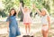 Smiling little girls stand with joyfully raised hands in park