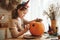 Smiling little kids girl making jack-o-lantern at home, drawing scary face on pumpkin