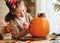 Smiling little kids girl making jack-o-lantern at home, drawing scary face on pumpkin