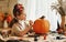 Smiling little kids girl making jack-o-lantern at home, drawing scary face on pumpkin