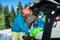 Smiling little snowboarder and mother help to dress up