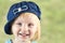 Smiling llittle girl with a cap on her head on a green background