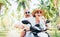 Smiling in love couple travelers riding motorbike under palm trees in their island vacation