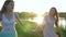 Smiling lovely girlfriends walk holding hands along meadow along loch