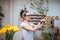 Smiling lovely young woman florist arranging plants