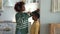 Smiling loving African American mother measuring height of her child son at home