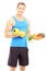 Smiling male athlete holding dumbbell and dish full of fresh veg