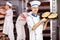 Smiling male baker posing with freshly baked breads in bakery