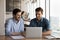 Smiling male colleagues cooperate together on laptop