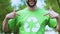 Smiling male eco-activist pointing finger on recycling symbol print on t-shirt