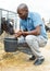 Smiling male farmer with bucket taking care young cattle at the cow farm