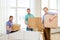 Smiling male friends carrying boxes at new place