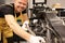 Smiling male locksmith repairing motorcycle with wrench in service center