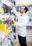 Smiling male pharmacist searching rows of drugs